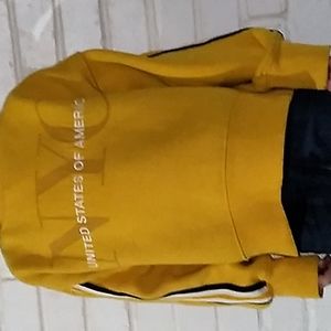 A yellow swet shirt with black white organ strips on both sides